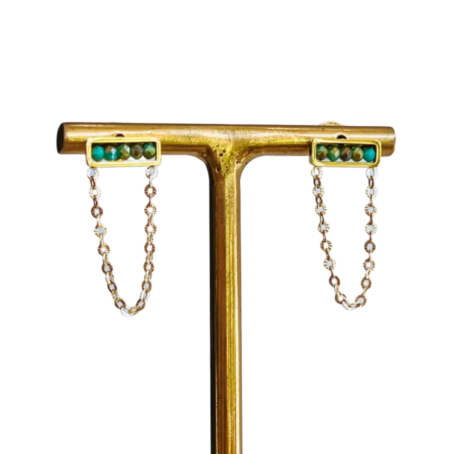 Abaco Chain Earrings - Aquamarine Gold earrings with green gemstones on t-stand on a light background