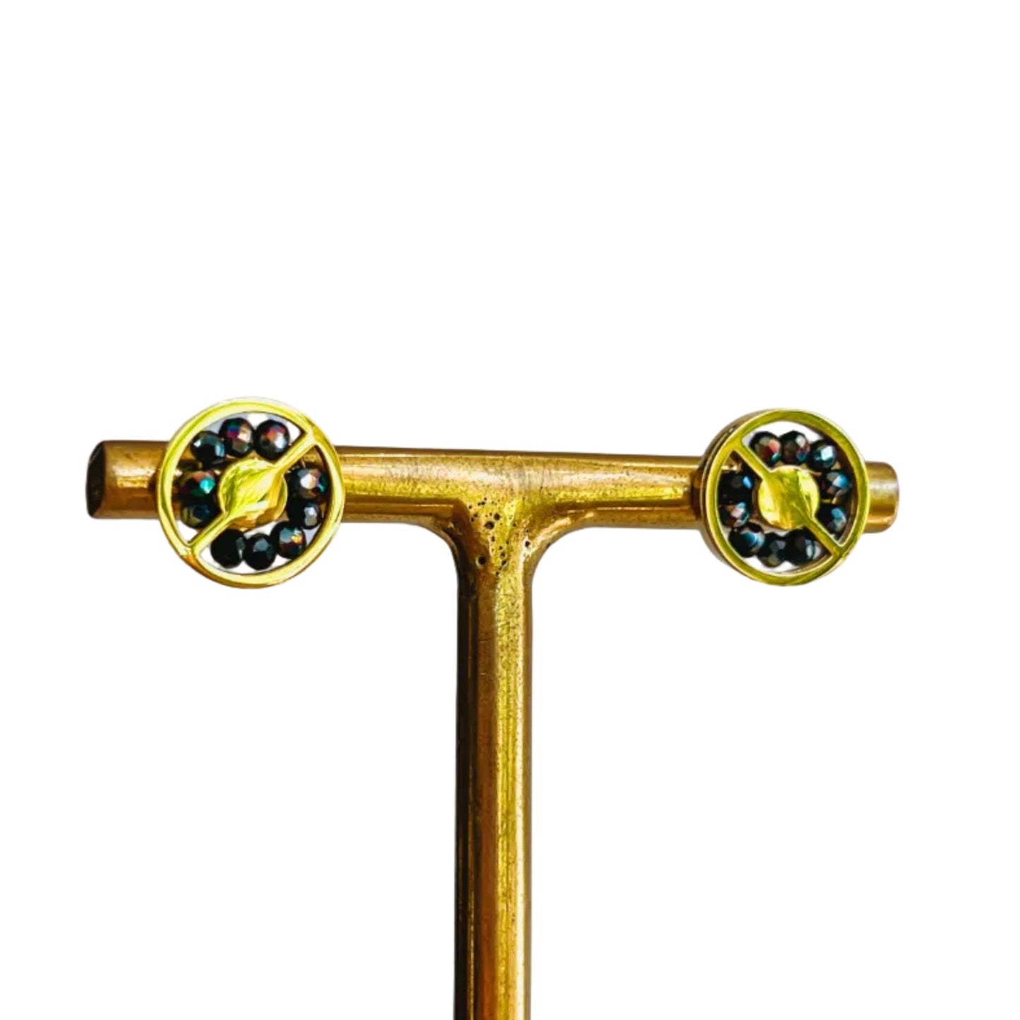 Abaco Stud Earrings - Midnight Gold earrings with purple and black gems on stand on a light background