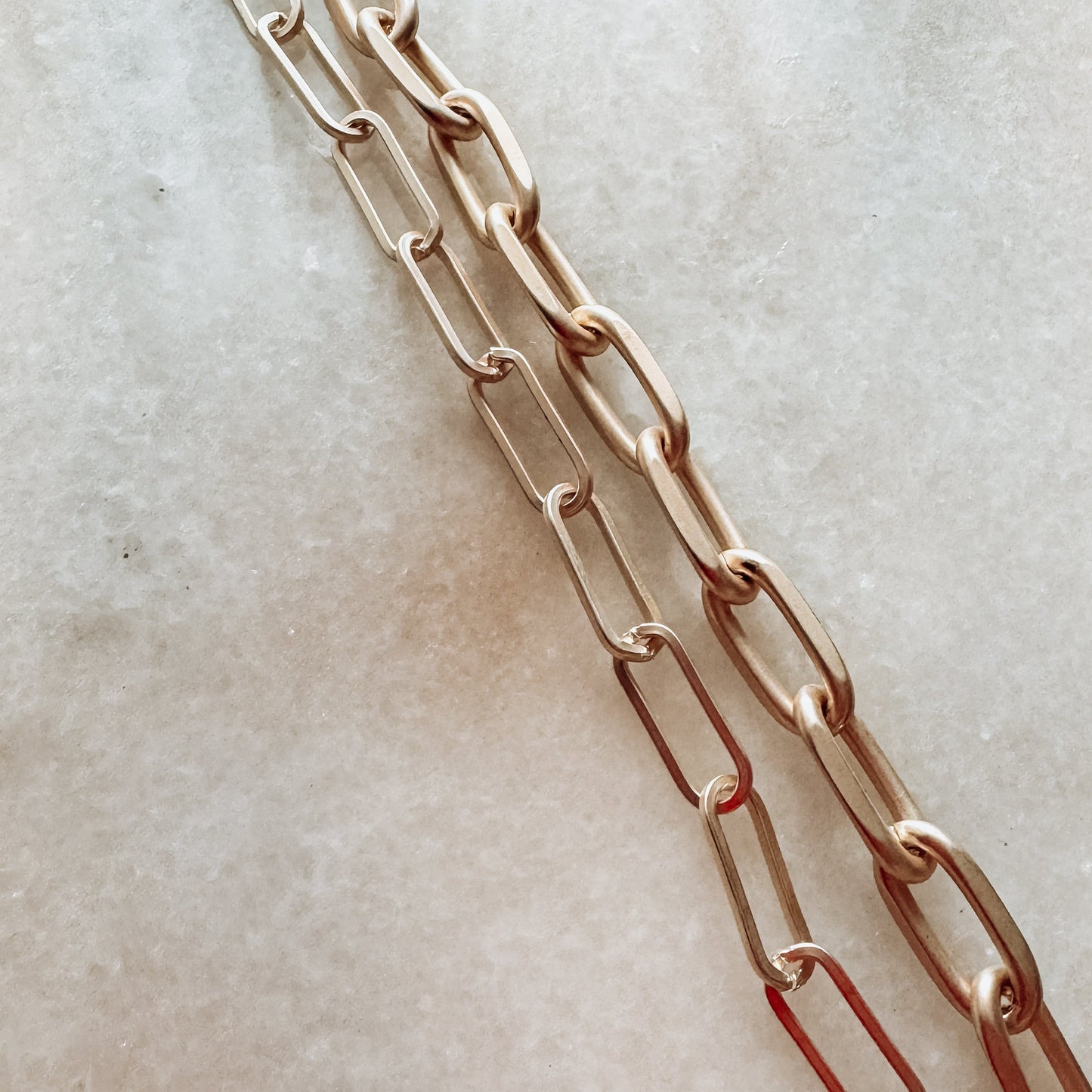 two different sized gold chain on a bright white surface