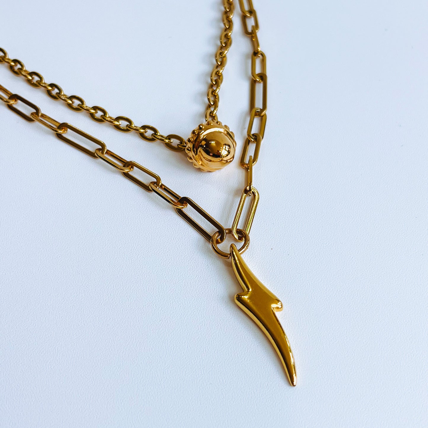 Bottom Double Necklace Gold layered necklace with two chains and pendants on a light background