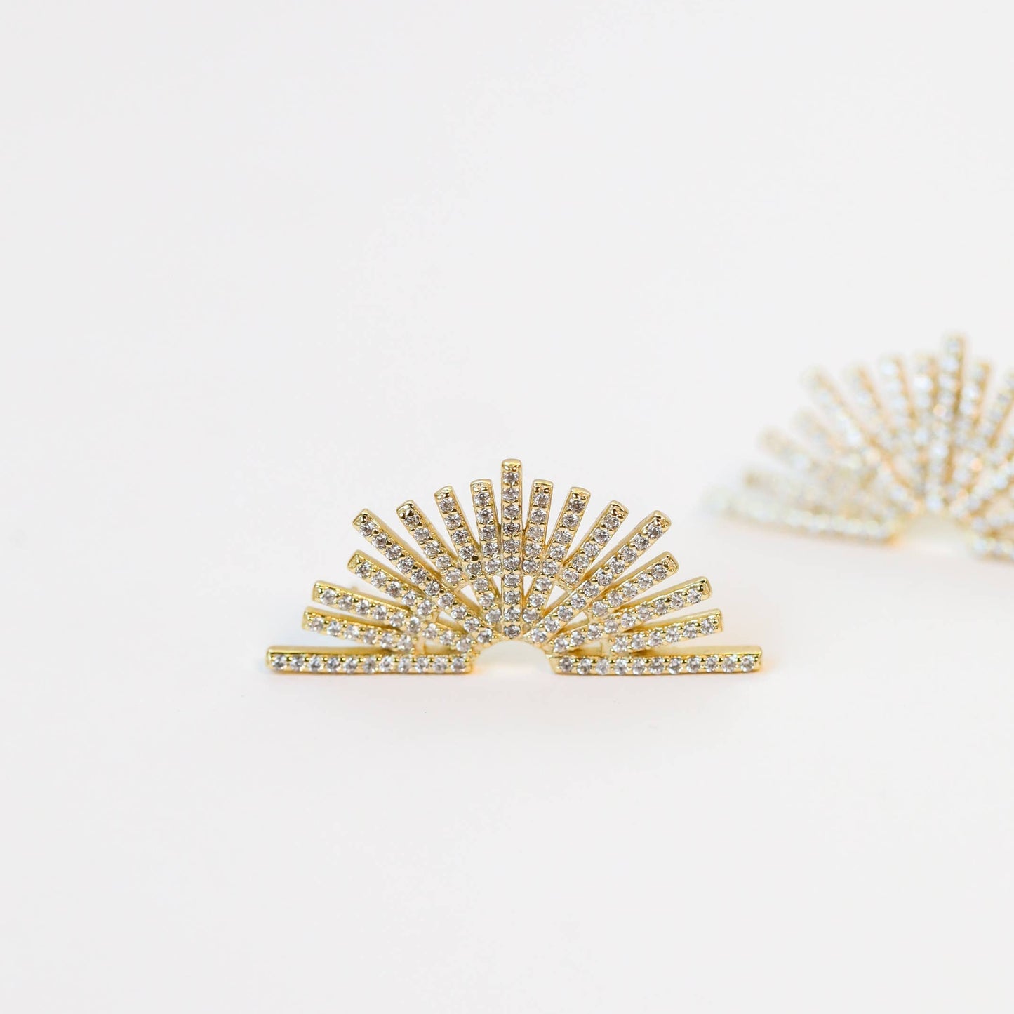 Celestial Gold Earrings - Sunburst Gold sunburst earrings on a light background laying on side