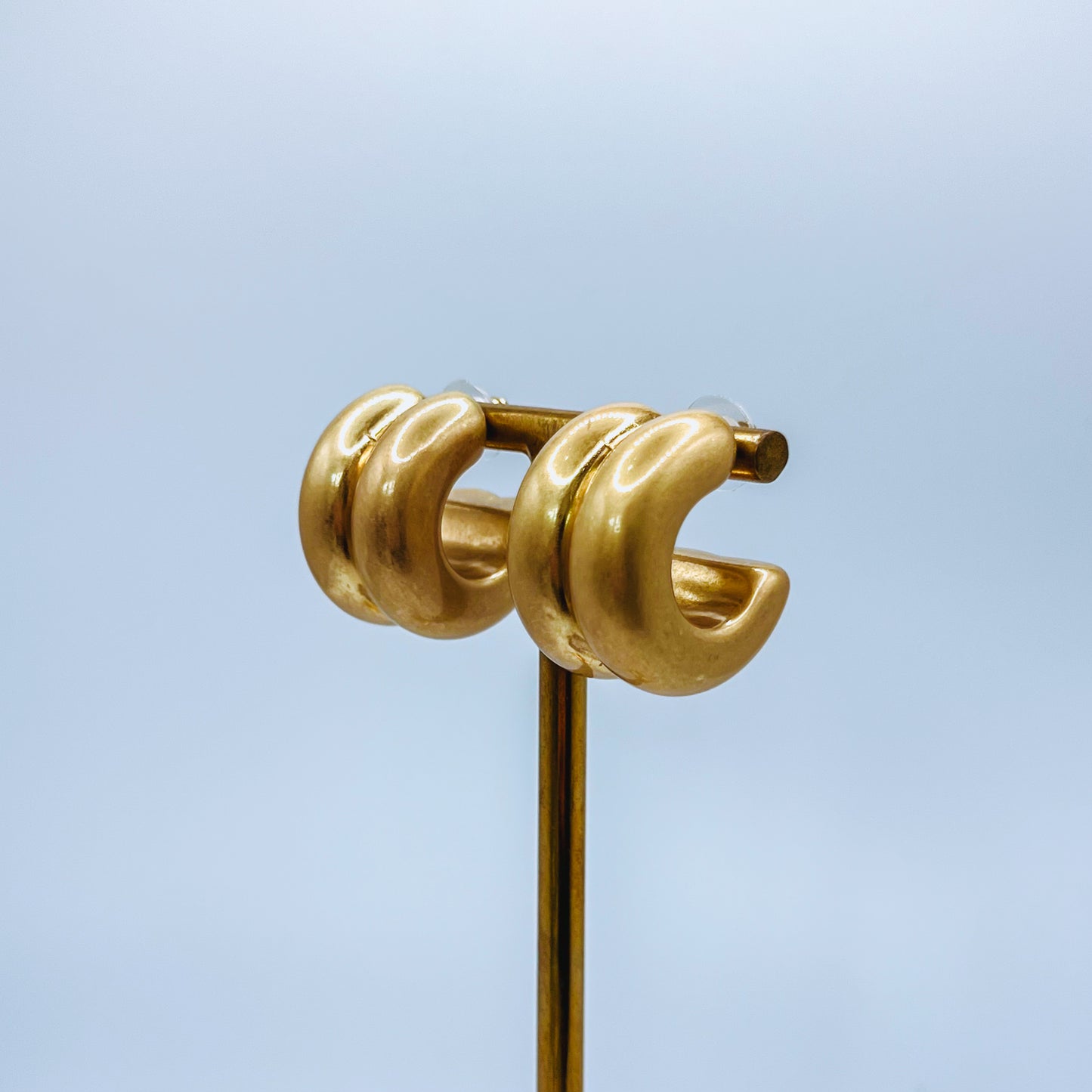 Chunky Gold Hoop Earrings Gold hoop earrings on gold earrings stand on a background