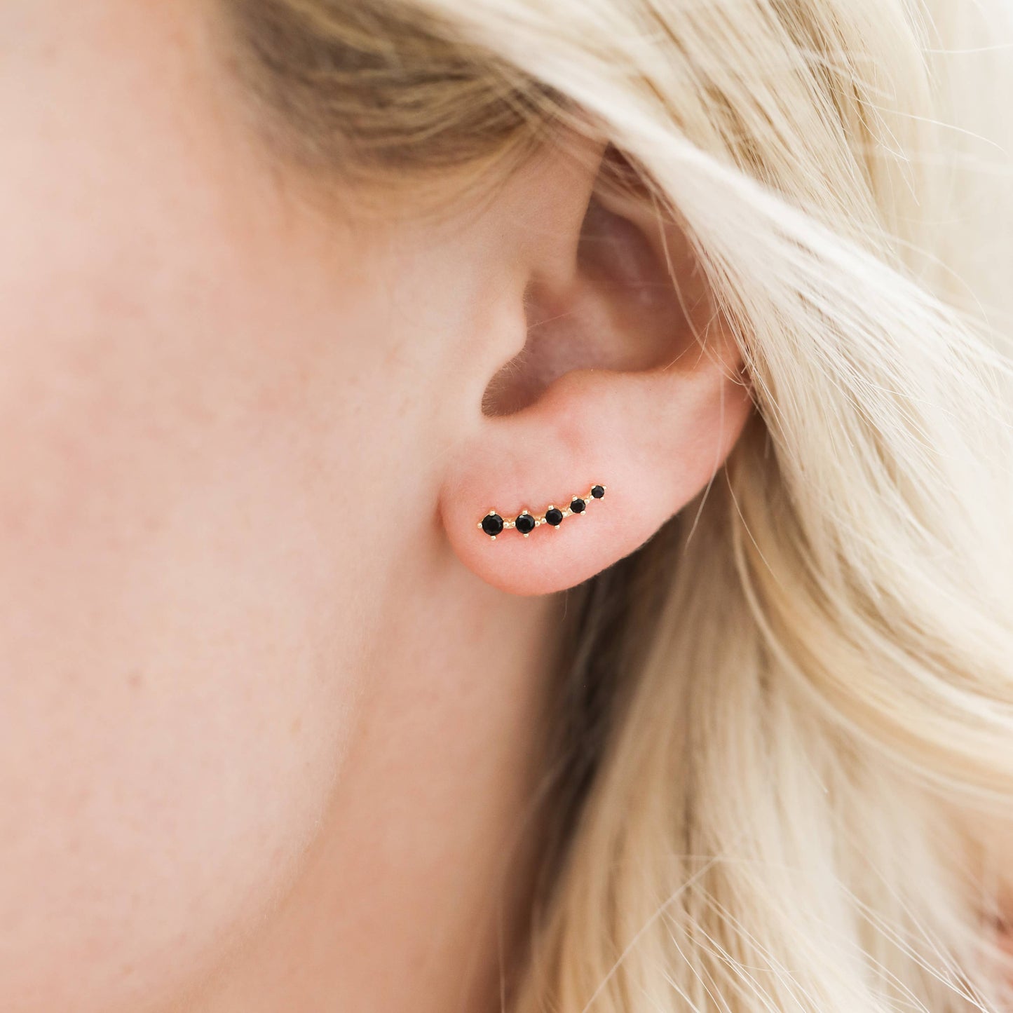 Crawler Gold Earrings - Black Close-up of an ear wearing a small earring with black studs.