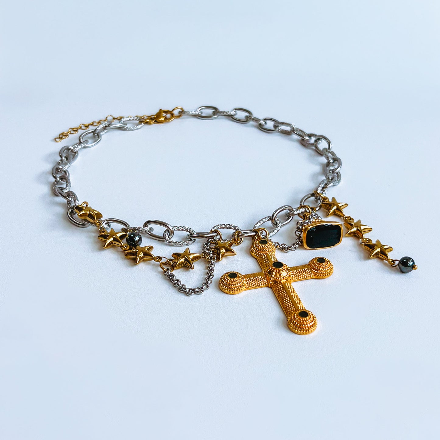 Cross Necklace chunky necklace with gold cross, black beads, and star charms on a light background