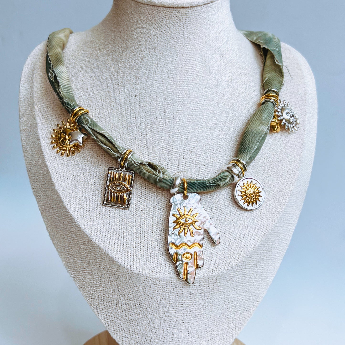 Denim Charm Necklace with denim fabric and various gold and silver charms on a mannequin bust against a light background