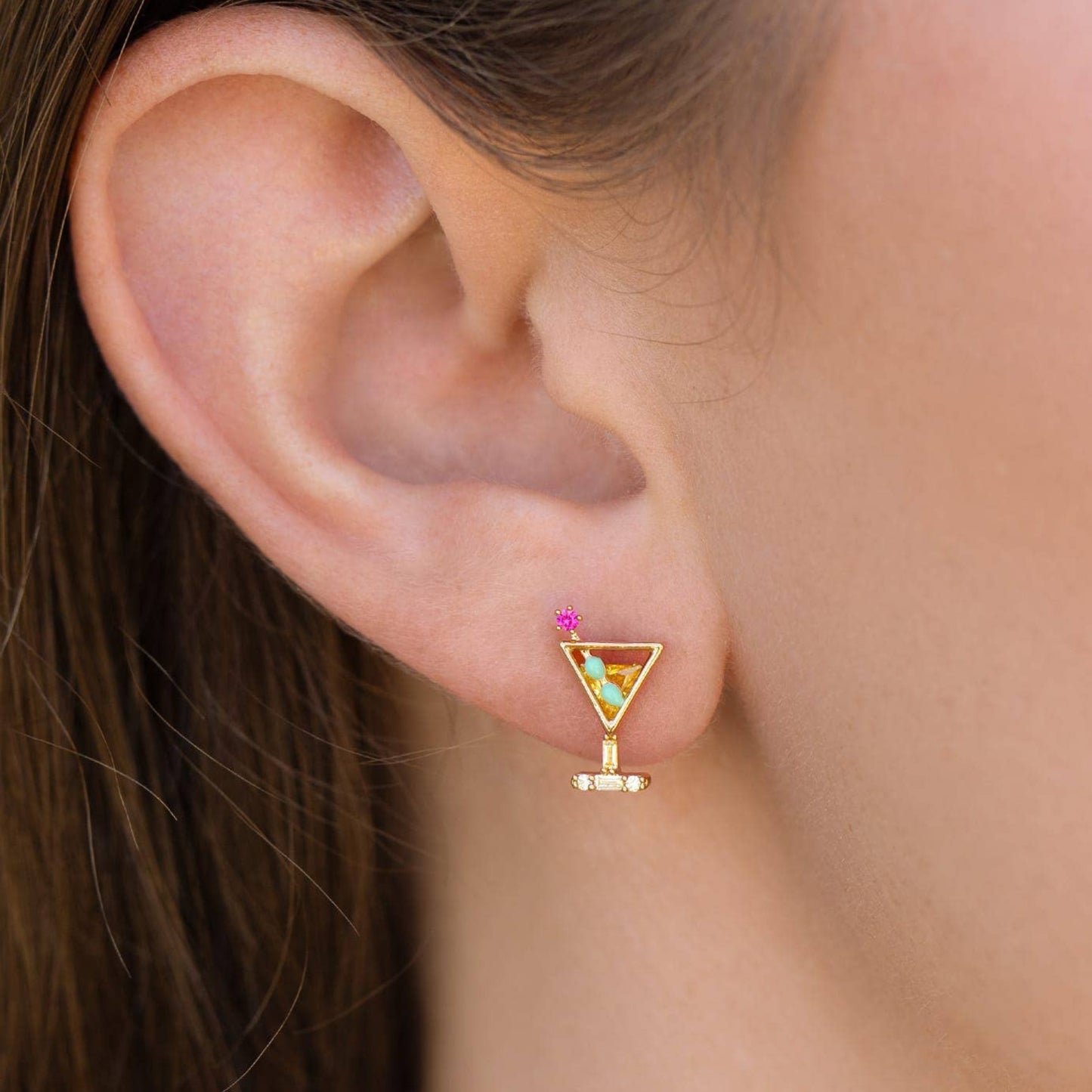 Dirty Martini Studs: Gold martini glass-shaped earring worn by a person with brown hair.