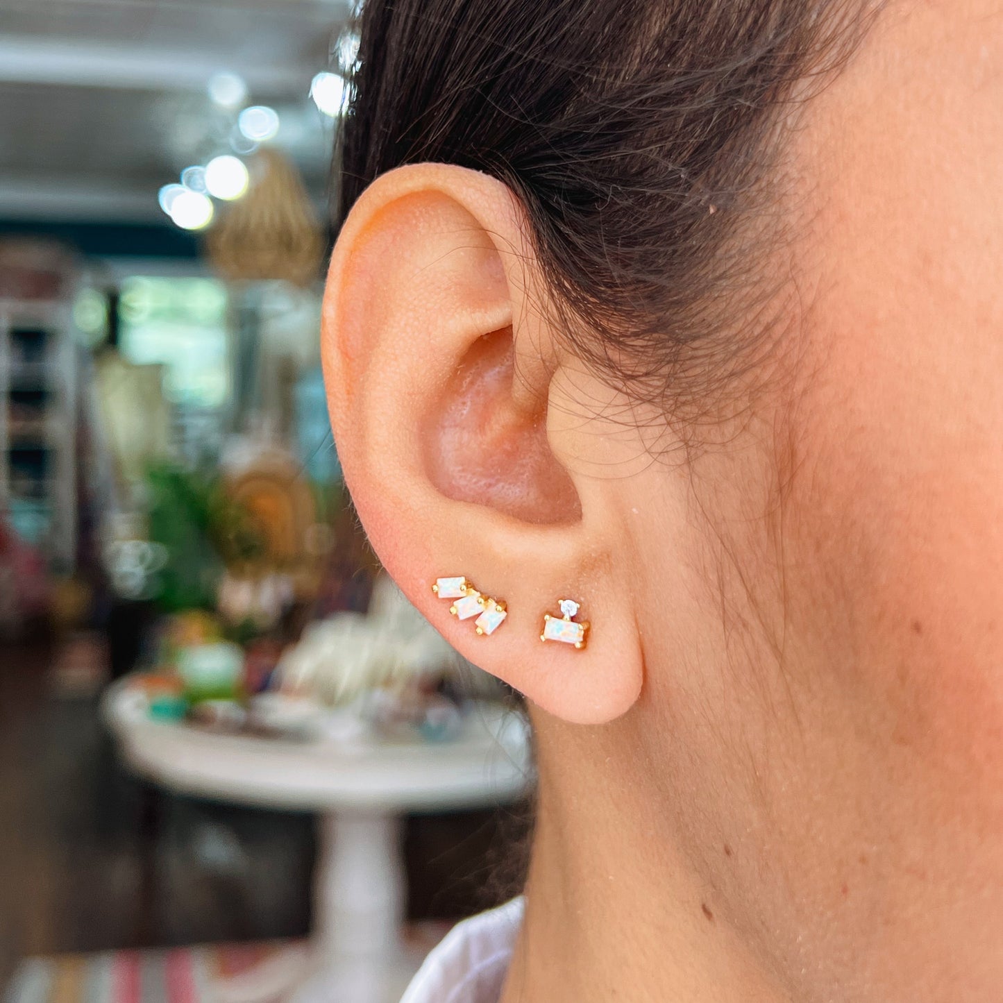 Double Stack Gold Stud - Opal White Close-up of an ear wearing two different gold stud opal earrings