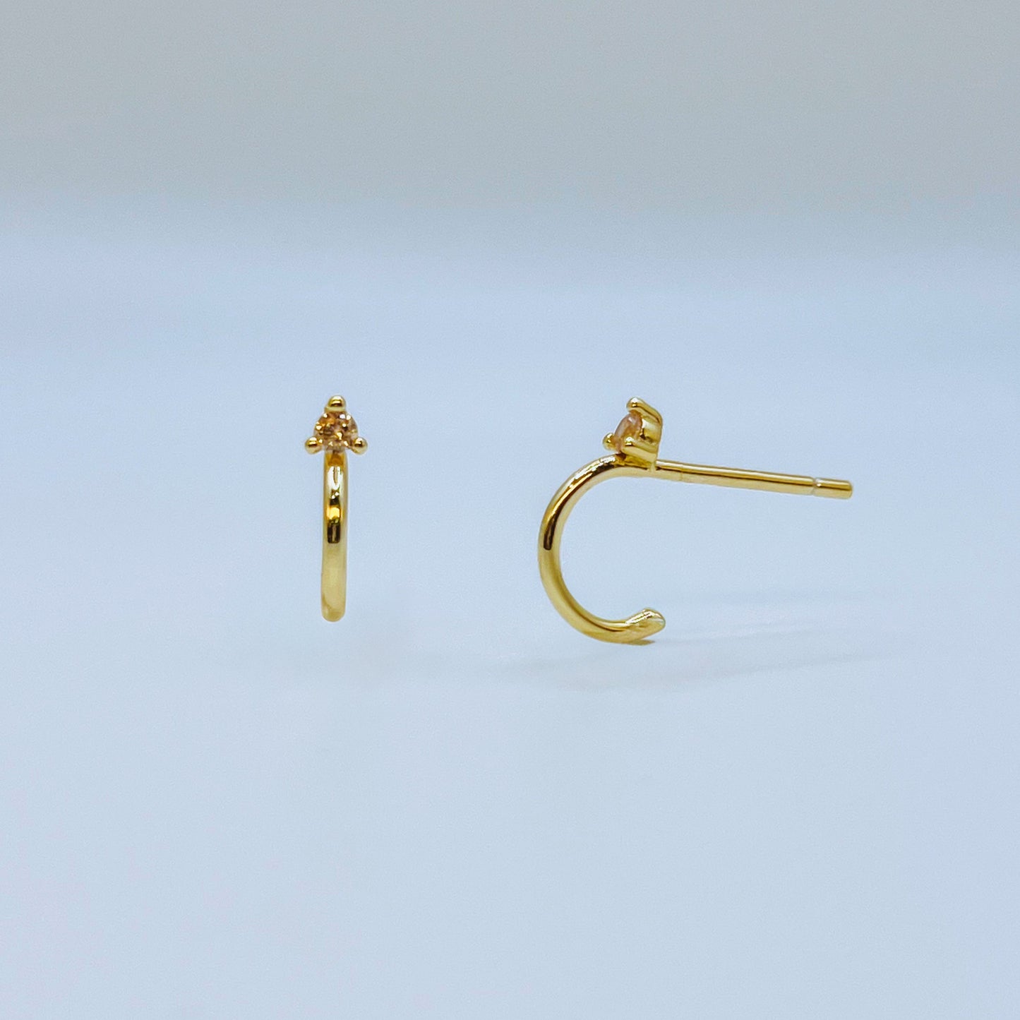 Gold Mini Hoop Earrings - Champagne Gold hoop earrings on a light blue background