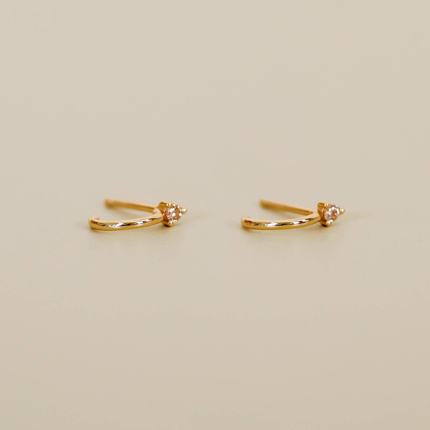 Gold Mini Hoops - Champagne Pair of gold hoop earrings champagne cz on a beige background