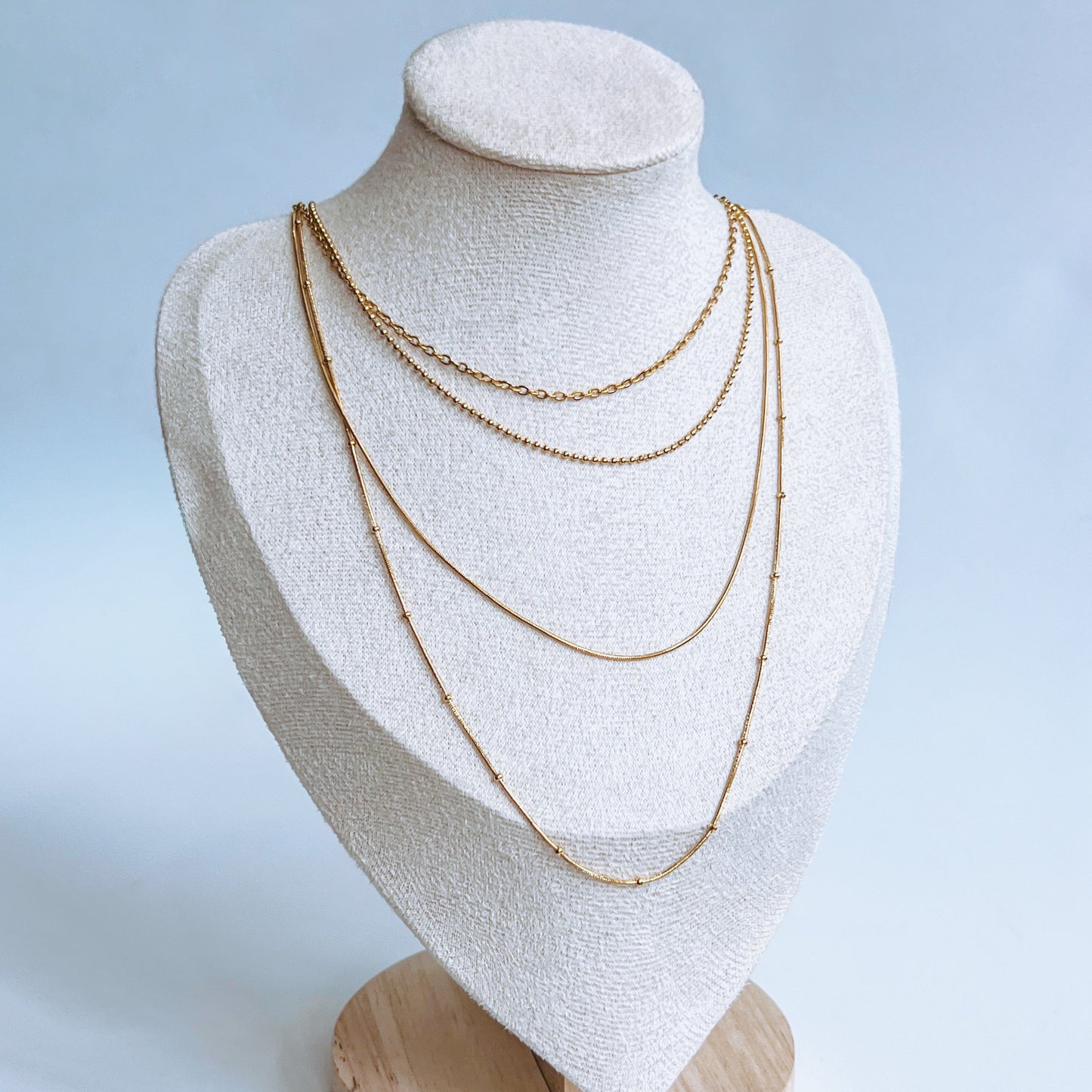 Gold Strand Layer Necklace with four gold chains on a white mannequin bust with a light background
