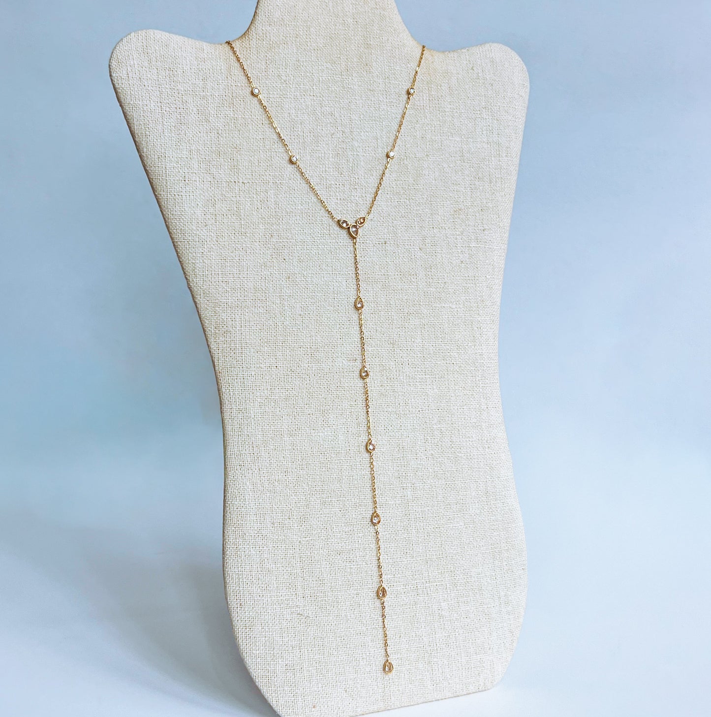 Gold stainless steel long Strand y shaped Necklace on a beige mannequin bust against a light background