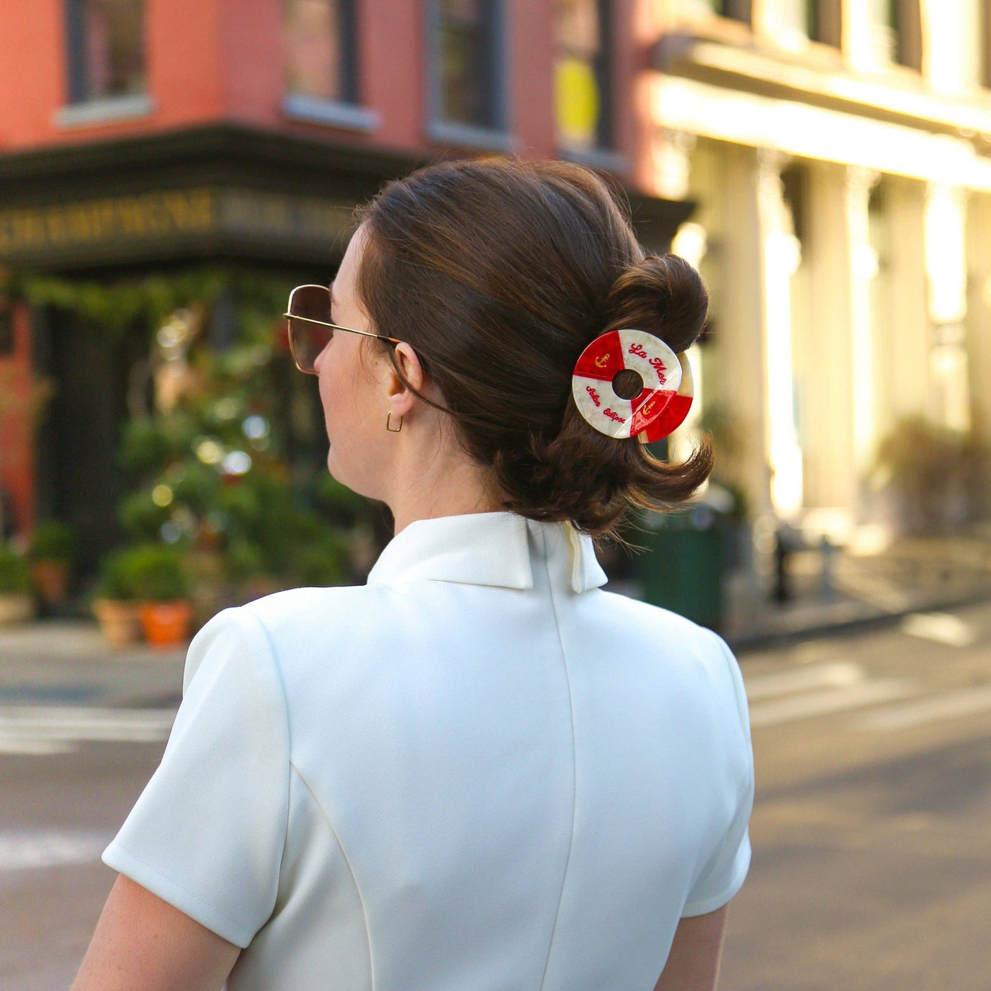 Woman with a Hand- painted black and white life buoy claw hair clip with 'La Mar' branding hair accessory walking down a city street