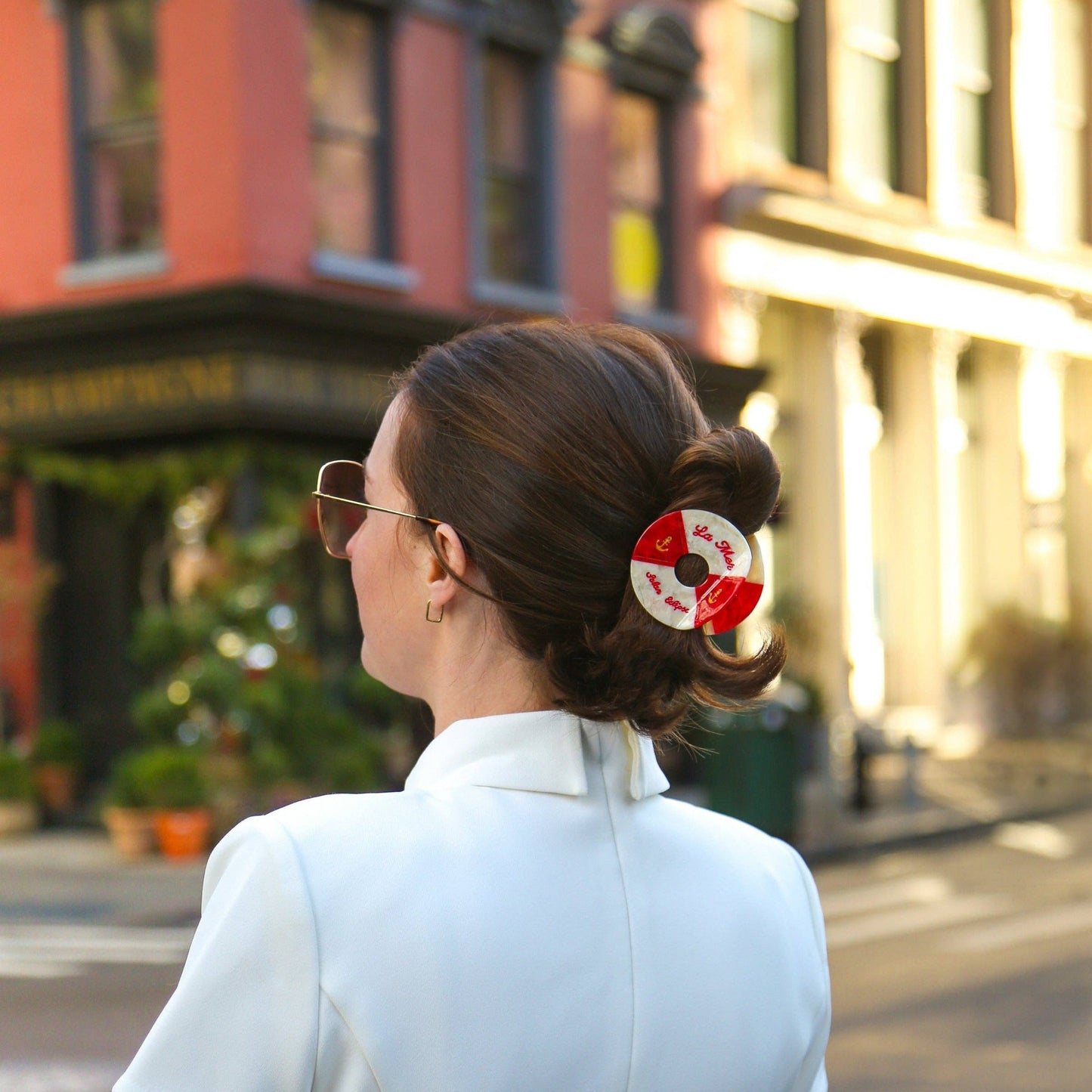 Woman with a Hand- painted black and white life buoy claw hair clip with 'La Mar' branding hair accessory walking down a city street