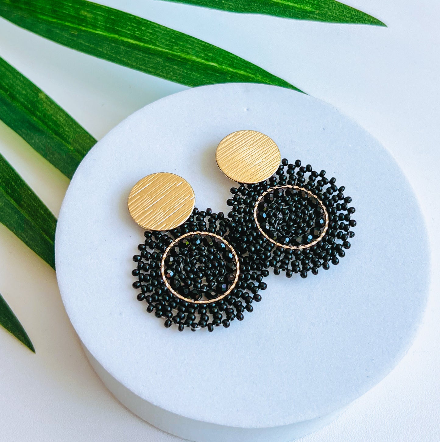 Helix Beaded Earring Pair of black beaded earrings with gold accents on a cushion