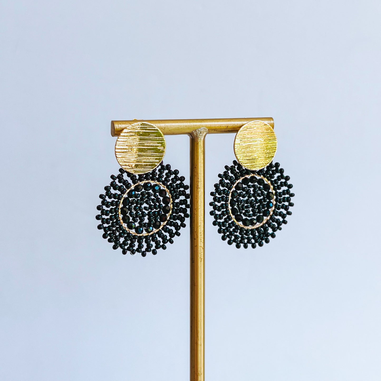 Helix Beaded Earring Gold and black earrings on a gold earring stand against a light background