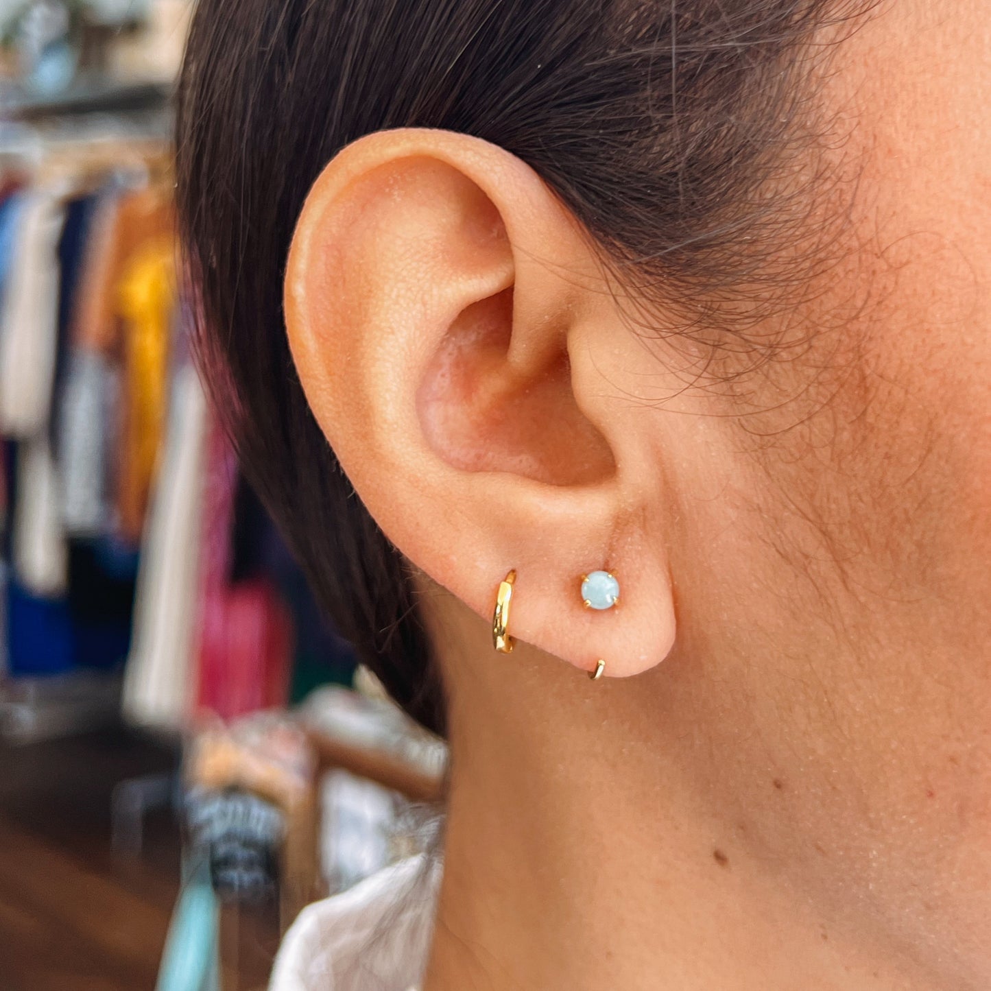 Huggies Earrings - Amazonite Close-up of an ear wearing gold hoop earrings with a blurred background.
