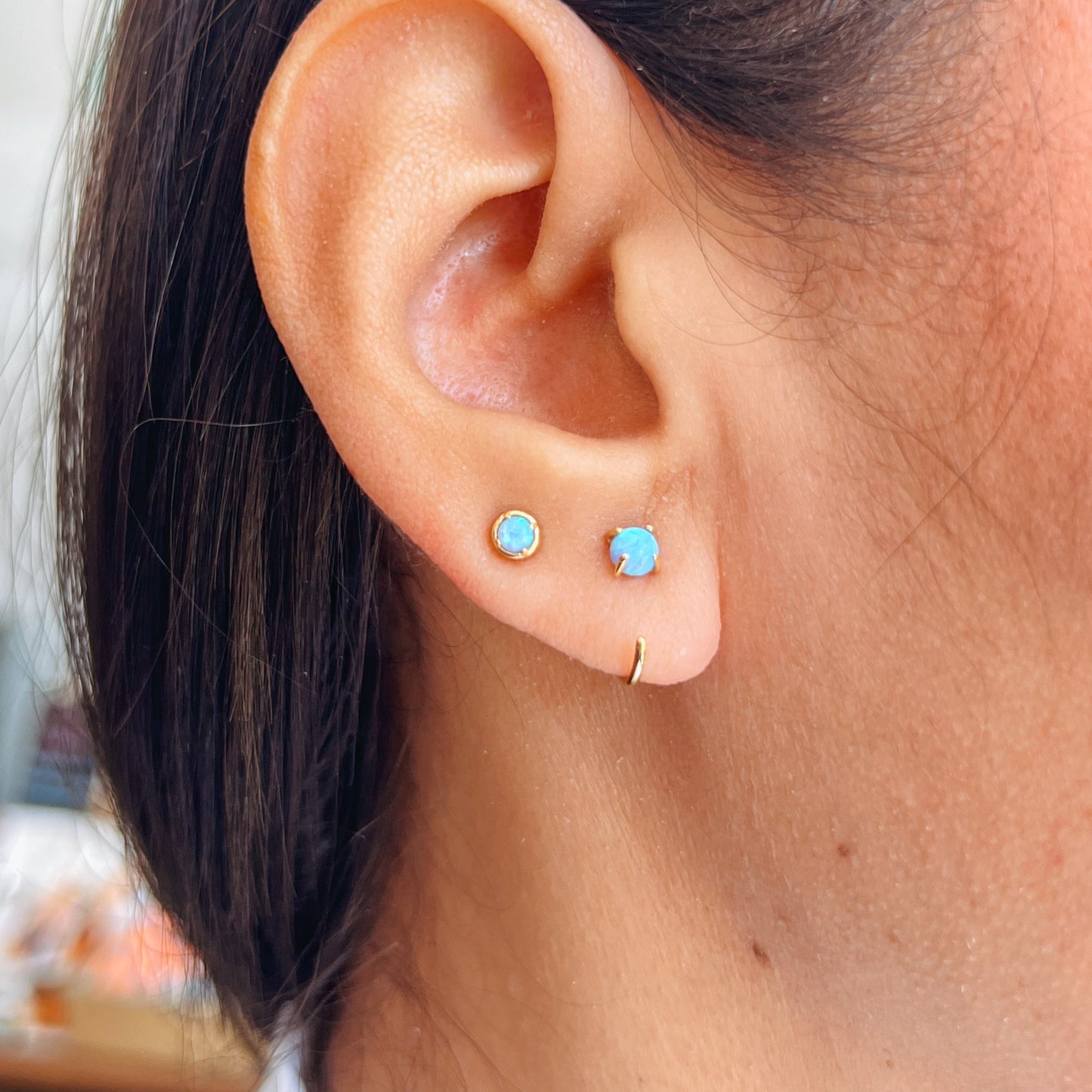 Huggies Gold Earrings - Fire Opal Close-up of an ear wearing two turquoise stud earrings 