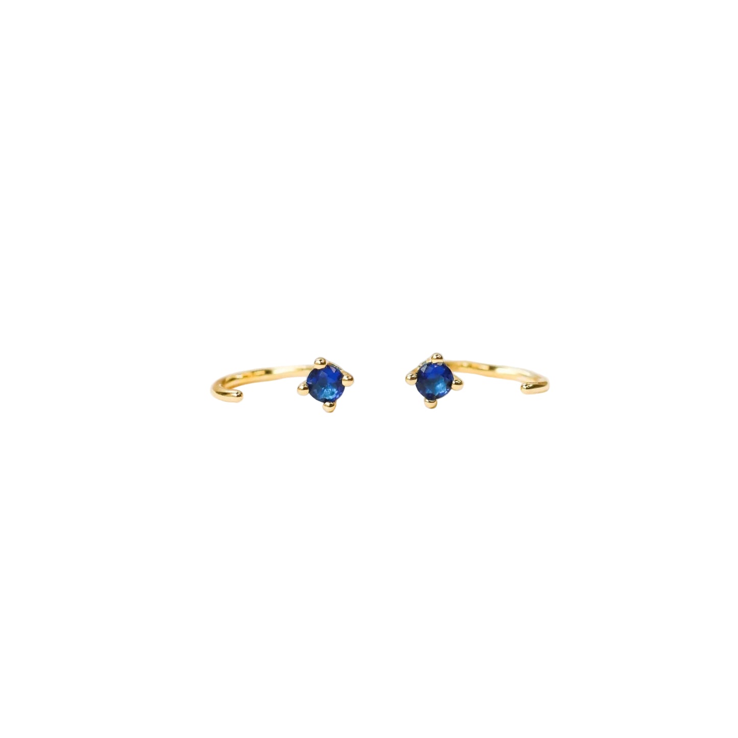 Huggies Gold Earrings - Sapphire Gold open ring earrings with blue gemstones laying on side 