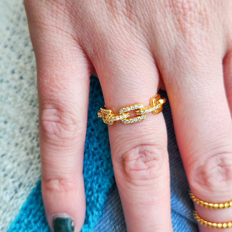 Gold chain ring on a finger with a blurred background
