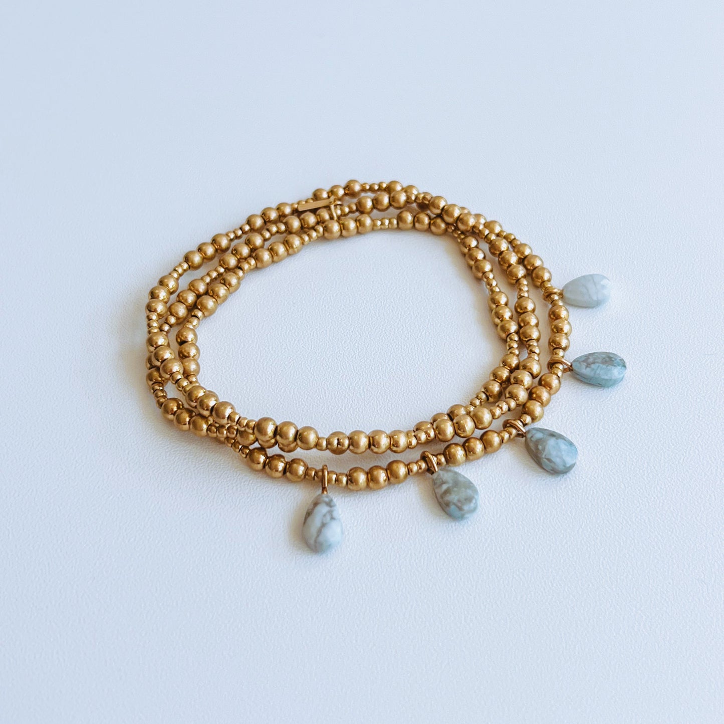 Metal Wrap - Gold & Grey Howlite Gold beaded bracelet with gold and gray beads on a light background