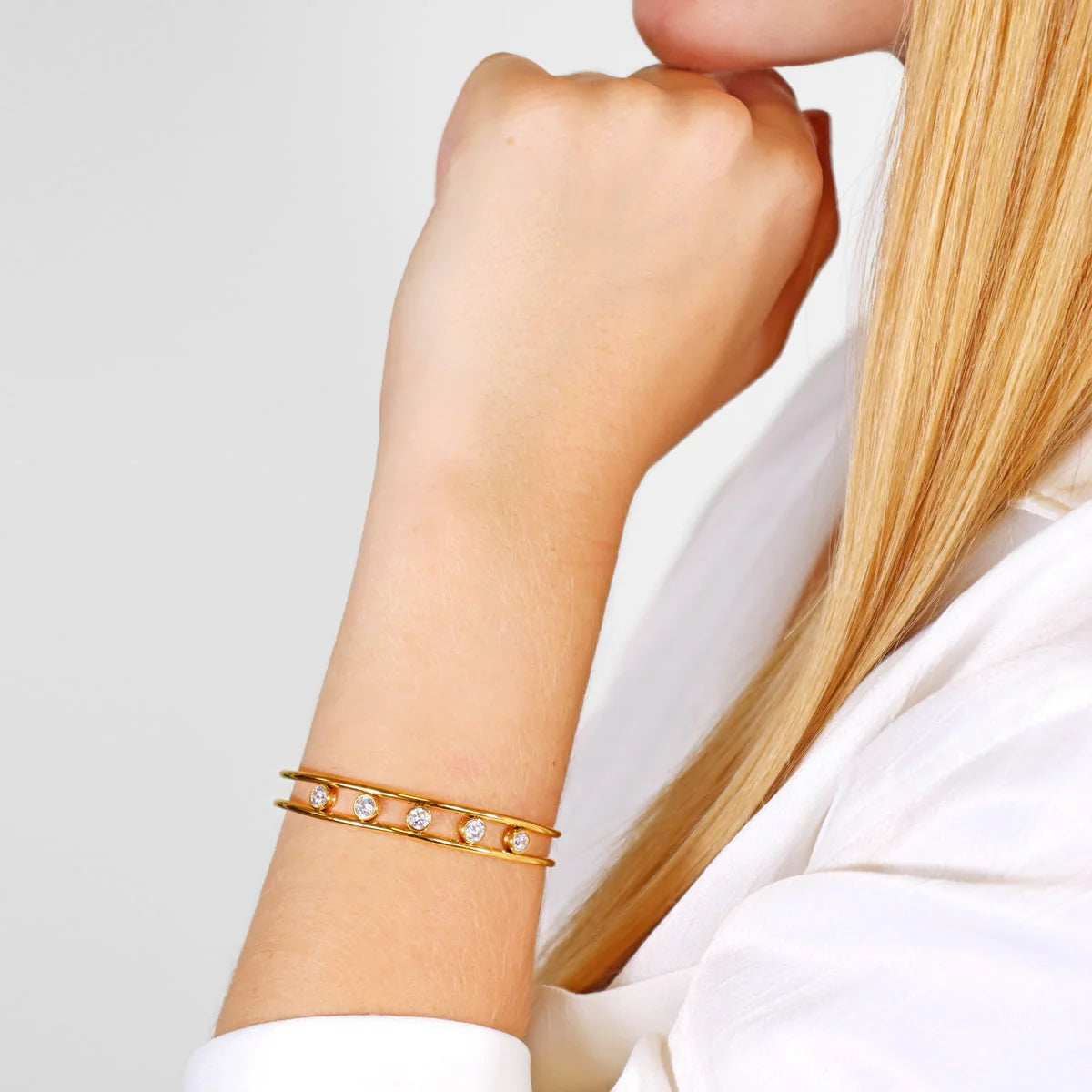 Multi Stone Cuff Gold bracelet with small diamonds on a wrist against a light background