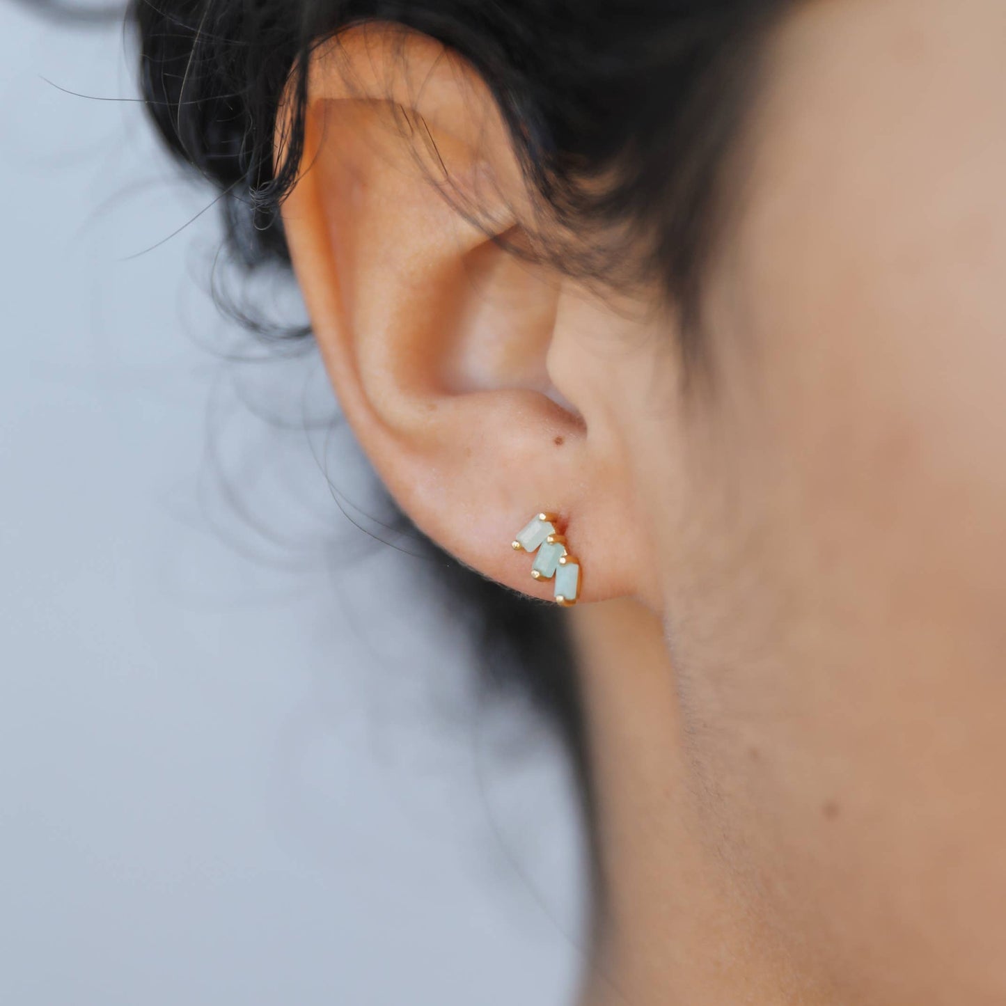 Offset Trio Earrings - Amazonite Close-up of an ear wearing a small earring with a blurred background