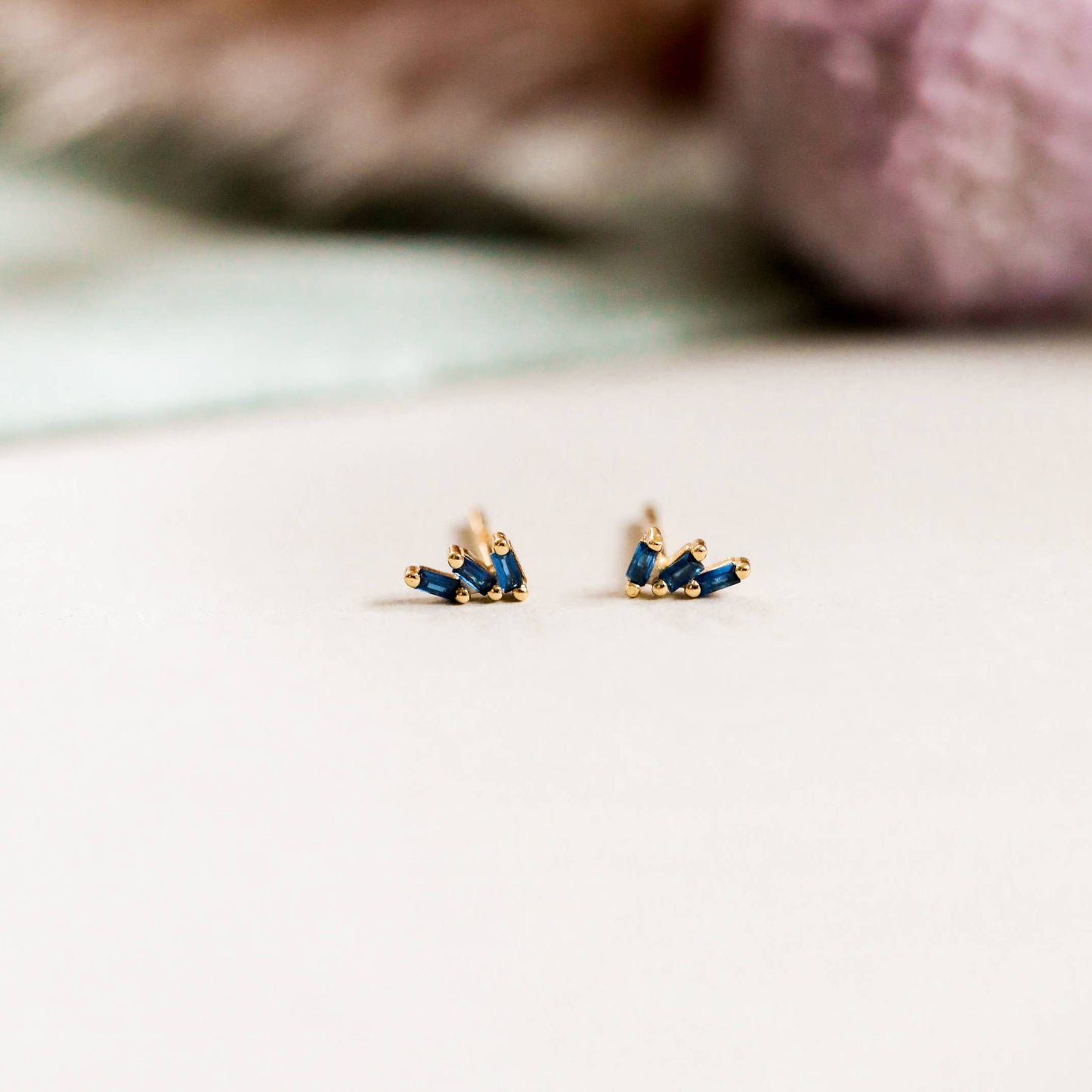 Offset Trio Gold Earrings - Sapphire Gold earrings with blue gemstones on a light surface 