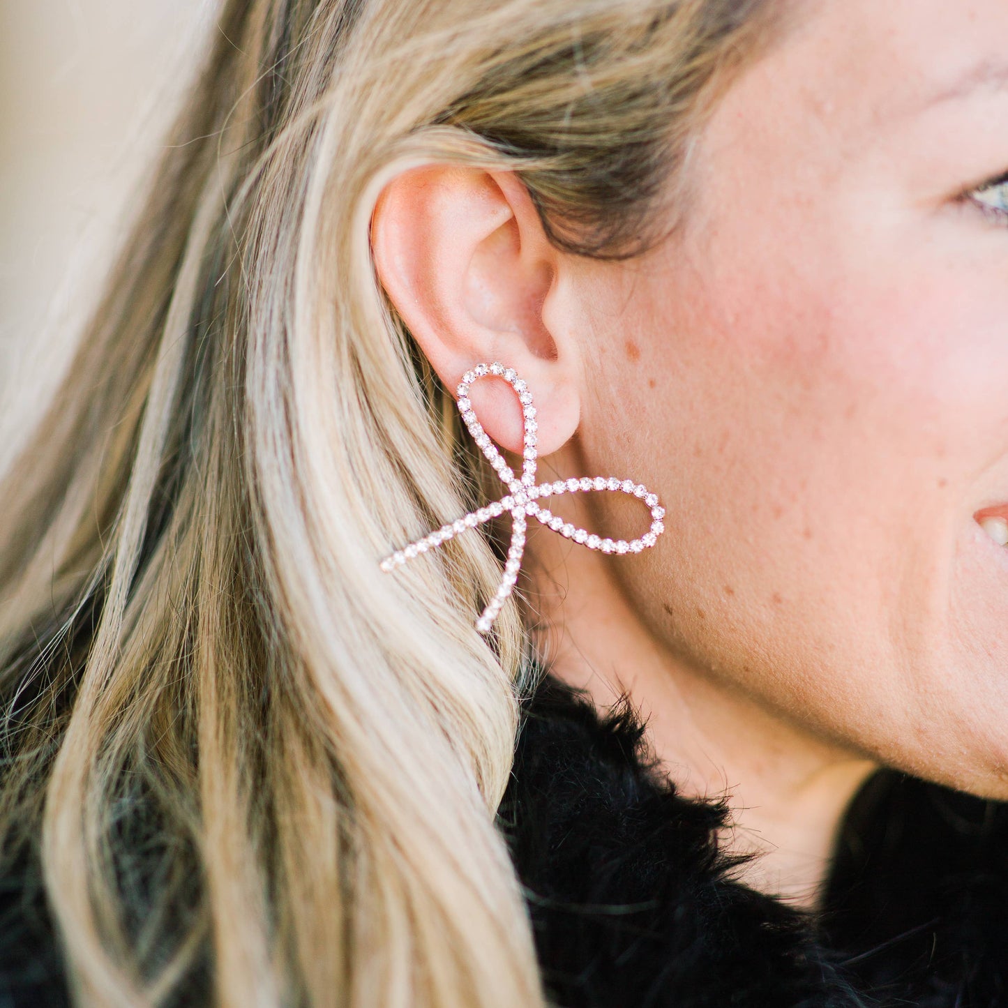 Pearl Statement Bow Earrings Close-up of a person wearing a bow-shaped earring with pearl details.