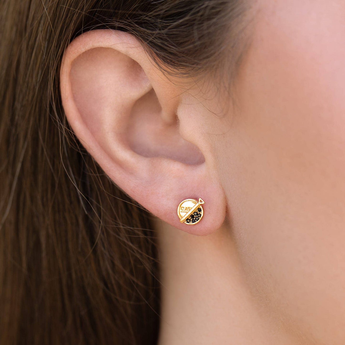 Premium Caviar Studs: Gold pated Gold earring with black gemstone worn by a person