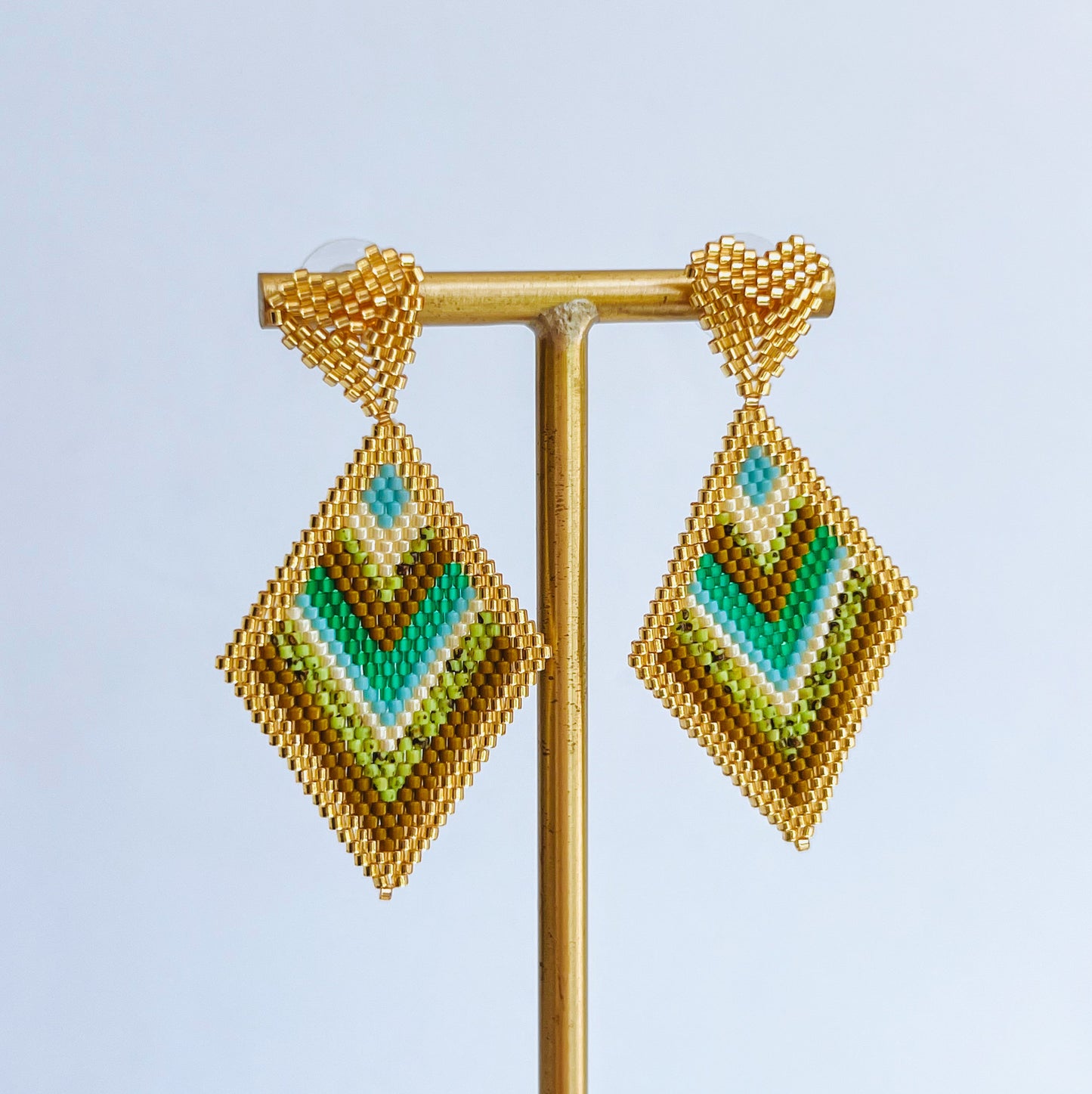 Sienna Beaded Earring Pair of geometric beaded earrings on a stand against a light background