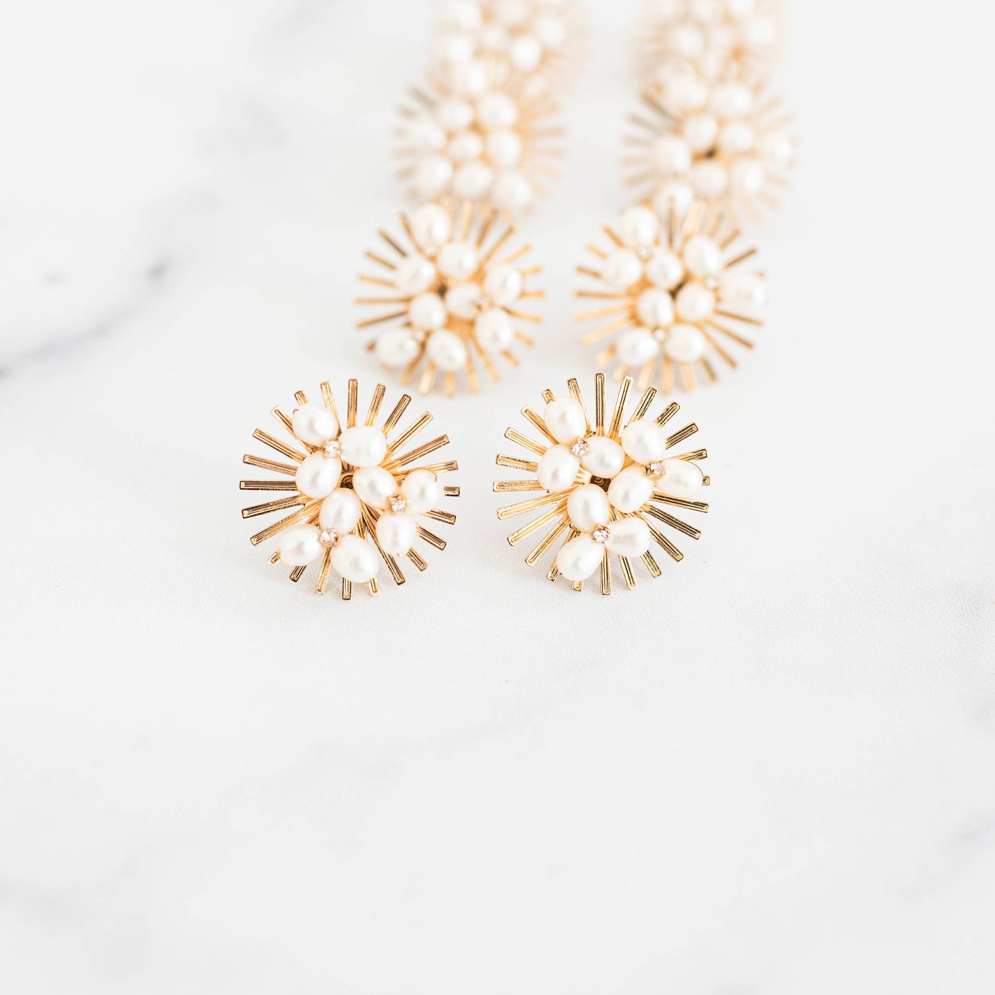 Sunburst Pearl Statement Stud Earrings arrangement of Gold earrings with pearl-like stones on a white background