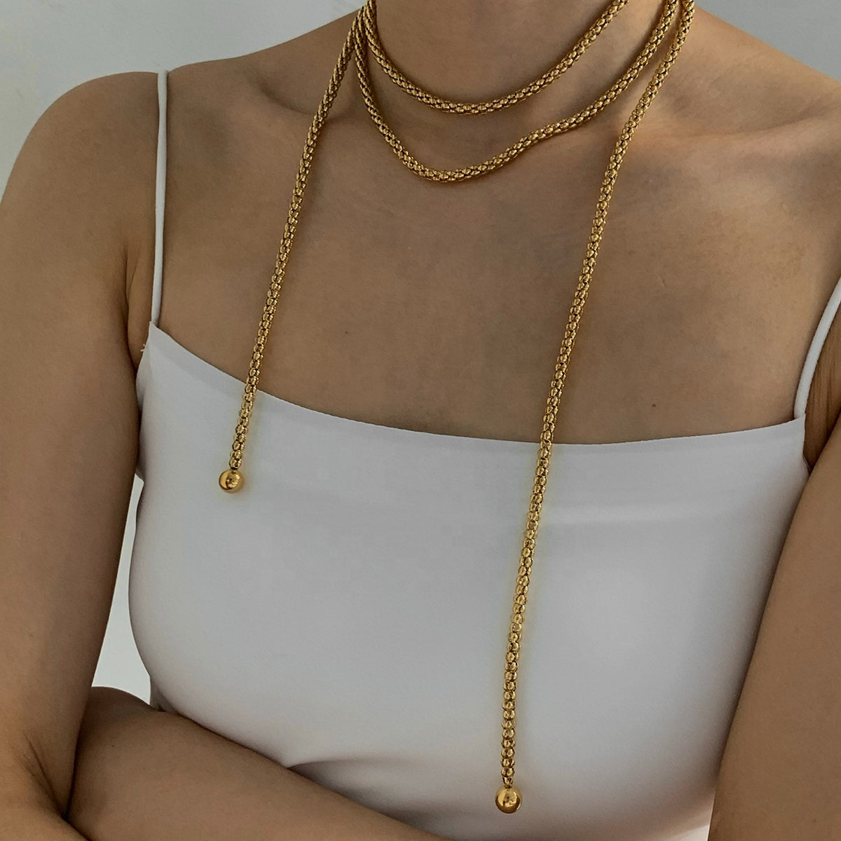 vintage Gold chain necklace on a person wearing a white top against a neutral background