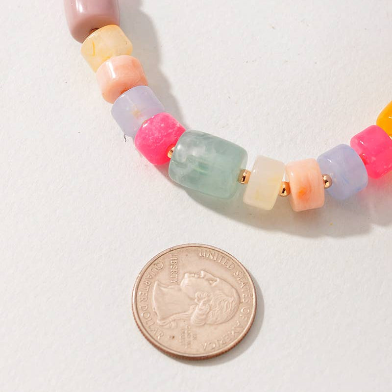 Colorful beaded necklace next to a U.S. quarter on a white background
