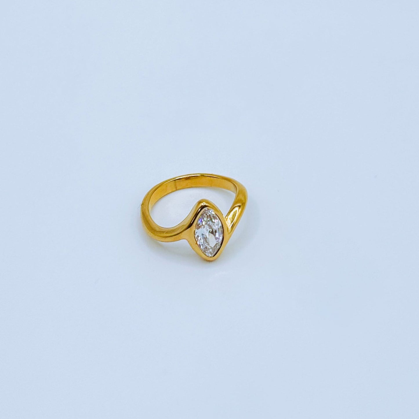 Gold ring with a clear gemstone on a light blue background